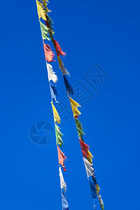 象征两排多彩的佛教祷告旗在蓝天背景风中挥舞和平丰富多彩的图片