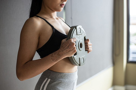 妇女在胸前用Dumbbell重量板锻炼胸部吸引人的哑铃图片
