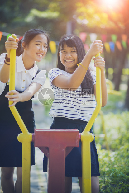 在公共游乐场上笑着脸的两名亚裔少年微笑愉快乐图片
