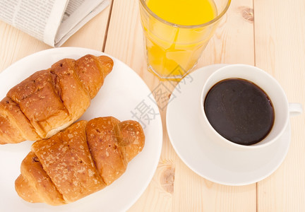 早餐饼干咖啡橙汁和木制桌面的报纸盘子一顿饭糕点图片