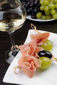 浆果一种美味的火腿和葡萄开胃菜加一杯白酒放在个斜缝上图片