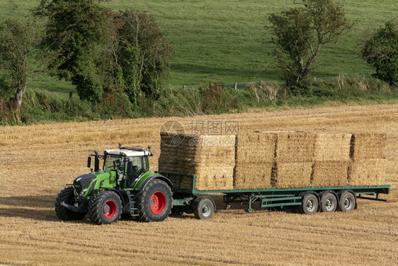 农业在联合王国北约克郡农田收割小麦后一辆拖拉机收集的干草成堆放拖拉机大包乡村的喂养图片
