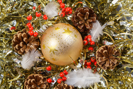 派对松果羽毛红浆和金色的黄瓜放在作为圣诞节装饰品的金色罐头上假期花环图片