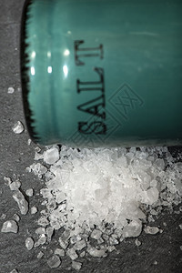 木头调味料磨碎的盐沙摇晃器和石黑桌上的研磨盐在陶瓷摇晃器周围切除白盐图片