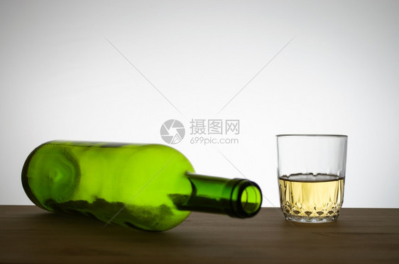 玻璃灰色的酒精绿葡萄瓶和木制桌上的白酒杯图片