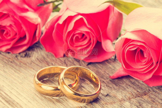 木制背景上带粉红玫瑰的婚环订金礼图片