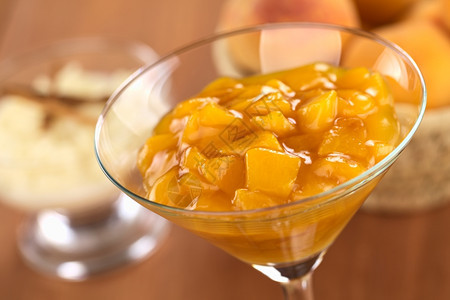 甜的第三新鲜桃子在鸡尾酒杯中装满了米布丁和一篮子桃后座有选择焦点玻璃集中三分之一顿饭图片