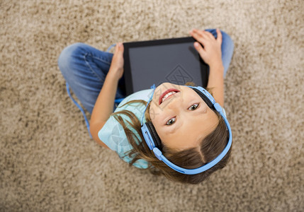 坐在地上使用平板电脑的小女孩图片