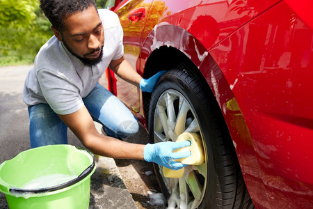 职业洗涤男人使用巴奇和海绵的代言人期间男子洗车轮图片