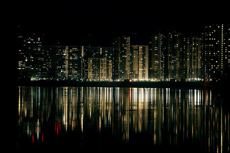 夜晚在间城市风景时摩天大楼在河流中出现反射黄昏图片