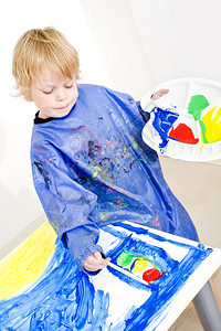 忙碌的创造蓝色年轻画家在一幅有海报油漆的画上给交通灯彩色图片
