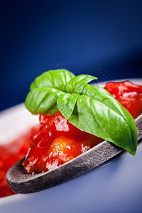 蓝色背景的新鲜意大利番茄酱有叶地中海调味料道图片