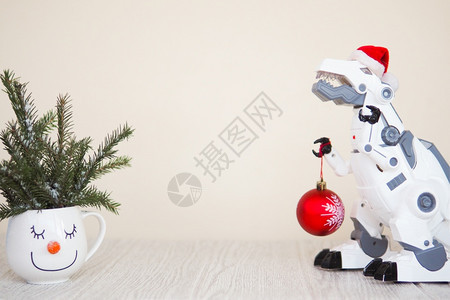 圣诞节冷杉一种玩具机器人恐龙在圣诞老人帽子与一个fir球和雪人杯与fir树枝在米色背景复制空间图片