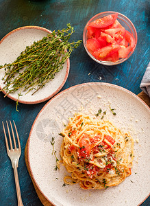 蓝色的食物最佳桌板上盘子的西红柿和百里香的意大利面条图片