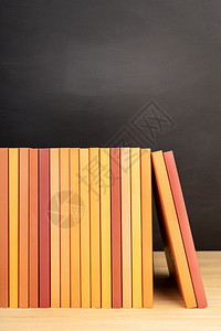 人们木制桌或板书架上的橙色籍组和背景黑板的橙色书籍组学习大图片