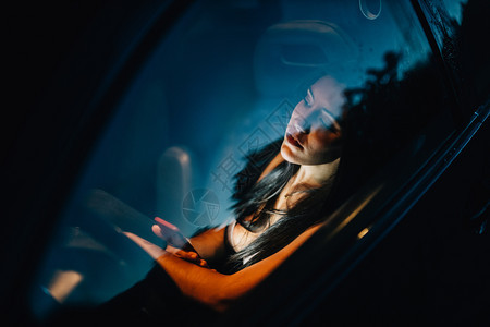 坐在车里的年轻女人从窗户向外看滴人造的年轻图片