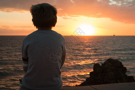 坐在海边看日落的男孩图片