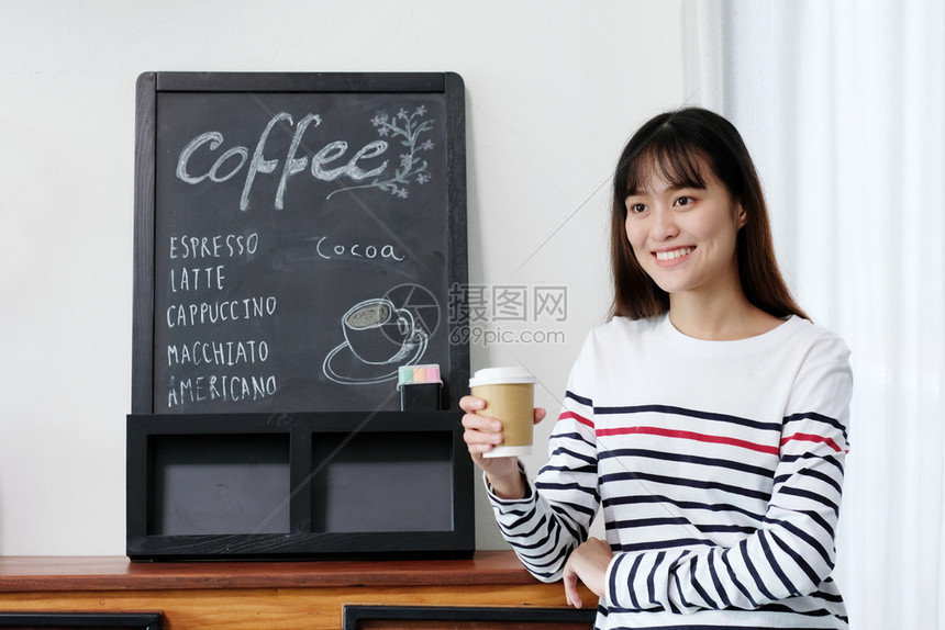 女士肖像年青的亚洲女在咖啡馆背景食品和饮料商业概念人们的生活方式中站立时拿着纸杯脱去咖啡的年轻女店铺图片