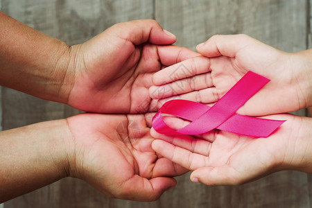 手握粉色丝带预防癌症概念图片