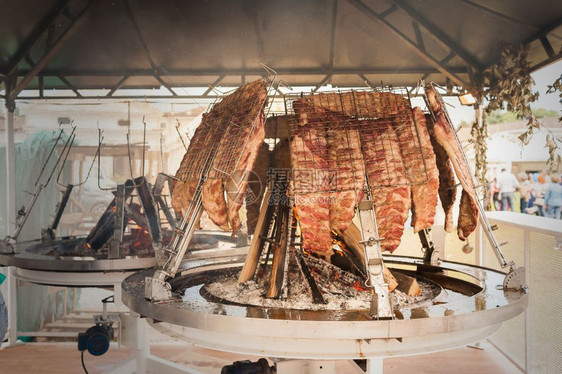 食物炙烤一种阿萨多根廷传统烤炉肉牛烧制在火堆周围的垂直烤架上图片