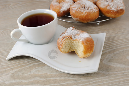 晚餐圆形的一杯咖啡和甜圈在一块盘子上的糖粉中早餐图片