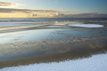 冬季清晨在波罗的海雪沙滩上升起阳光中云彩的美丽反光照耀着日出思早晨图片