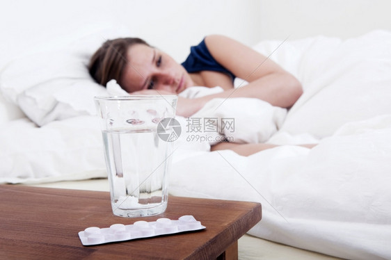 休息痛发烧床边的桌有一杯水还个带药丸和醒着生病的女人泡水带图片