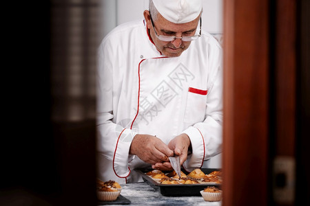 面包师把巧克力放在一个带松饼的钢盘上制造不良生产图片