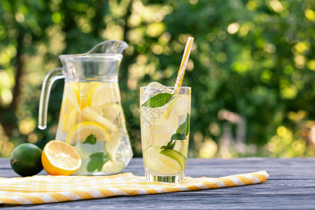 水果茶杯和玻璃中的柠檬木板上加的与石灰天然绿色背景夏季清新饮料罐中加柠檬玻璃以及木板上加柠檬鸡尾酒水图片