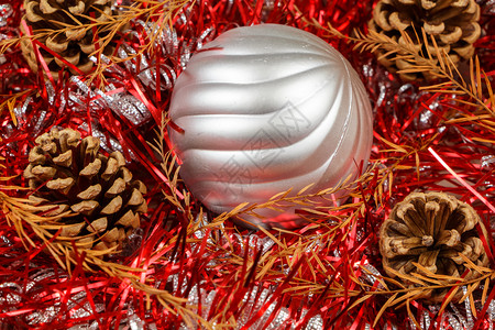 树叶松果死子和银色的花生在红上作为圣诞节的装饰品假期花环背景图片