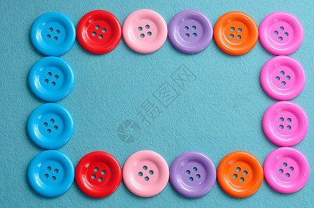 粉色的服装裁缝在蓝色背景上构成边框的多色按钮图片
