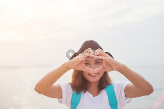 年轻女做心脏形状的女人夏日时光水平室外海边滩背景地平线洋黑色的图片