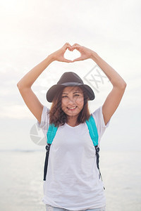 年轻女做心脏形状的女人夏日时光水平室外海边滩背景享受水平的爱图片