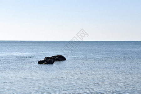 平静蓝水中的黑石海景平静云图片