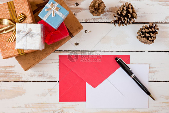 封上圣诞信和笔挂在有礼物和松果的生锈木制桌子上封圣诞信挂在生锈木制桌子上十二月木制的红色图片