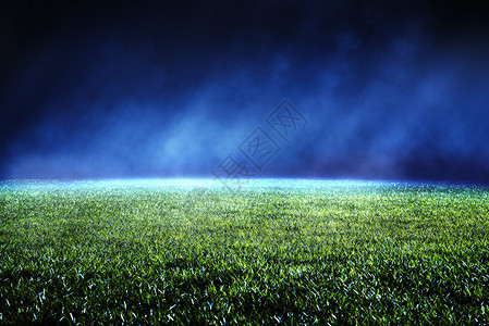 操场胜利团队在足球场保留草坪的景象光线照亮在对角方向喷雾的光线夜中低视和轻光效应图片