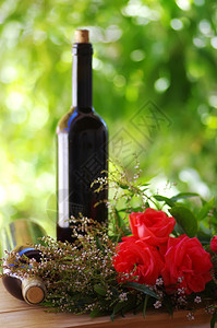 情人节赤霞珠浪漫木制桌上有红葡萄酒瓶子的玫瑰花图片