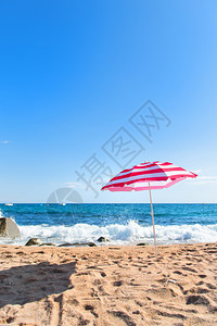 清空海滩有浪和条纹粉红色阳伞夏天假期西班牙图片