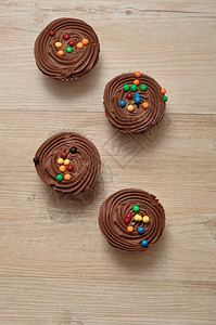 诱惑巧克力杯饼霜冻和彩色糖果装饰的巧克力蛋糕磨砂刨冰图片