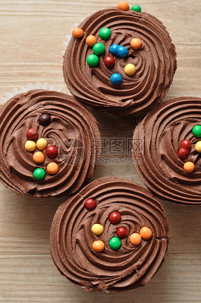 结霜巧克力杯饼霜冻和彩色糖果装饰的巧克力蛋糕磨砂甜的图片