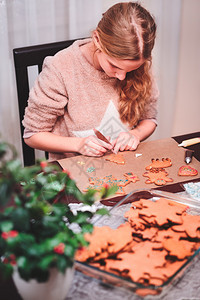 传统的女孩装饰烤圣诞红姜饼干配巧克力笔烘烤结霜图片