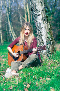 夏天金发女孩在草地上弹吉他漂亮的音乐家年轻图片