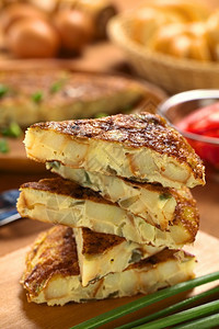 蔬菜重点新鲜的自制西班牙玉米饼煎蛋卷土豆和洋葱片堆在木切板上选择聚焦在上玉米饼片的前边缘正面图片