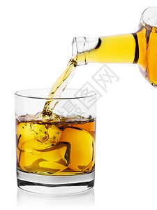 精神立方体金子在玻璃杯中从一瓶麦芽威士忌中倒入冰块从白色背景中分离出来在玻璃杯中图片