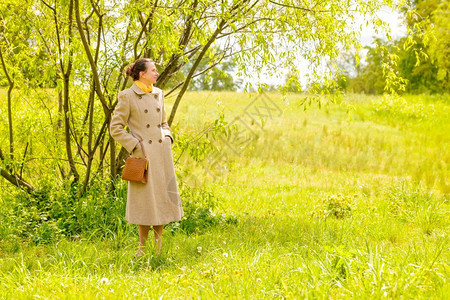 一种位优雅的高级女商人穿着大衣和黄色围巾在春日下公园等候时尚高级的图片