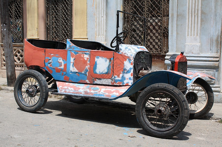 老式的衰变古巴哈瓦那街上一辆彩色破烂的开着高顶旧车汽图片
