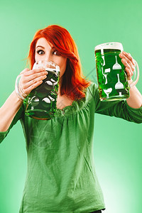 庆典照片来自一位美丽的红发女人持着并喝两杯盛大的绿啤酒女士漂亮的图片