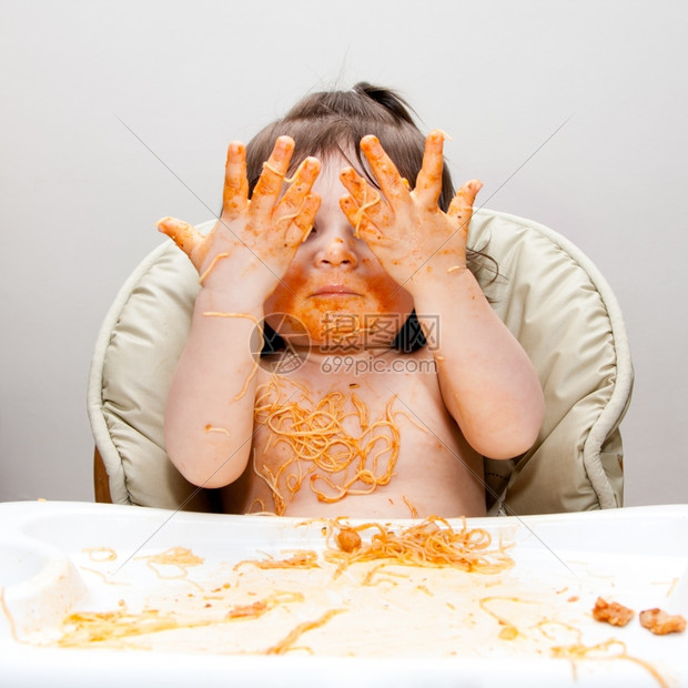 快乐的婴儿吃着乱七八糟的美味展示双手覆盖在意大利面香水上红番茄酱头发学步的儿童西班牙裔图片