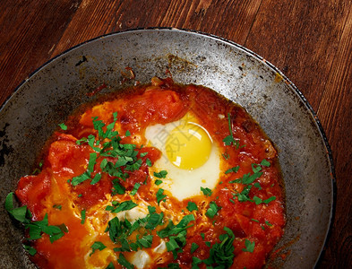 Shakshuka在西红柿酱辣椒和洋葱中偷吃鸡蛋通常以烹饪莫罗干菜突尼斯利比亚阿尔及和埃的烹饪为香料煎蛋卷番茄象征图片
