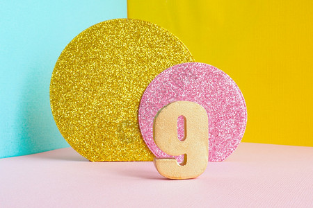几何学9号金色黄在多彩蓝色粉红背景和两个闪亮的金子和粉红色圆圈生日快乐贺卡概念的极简主义图片